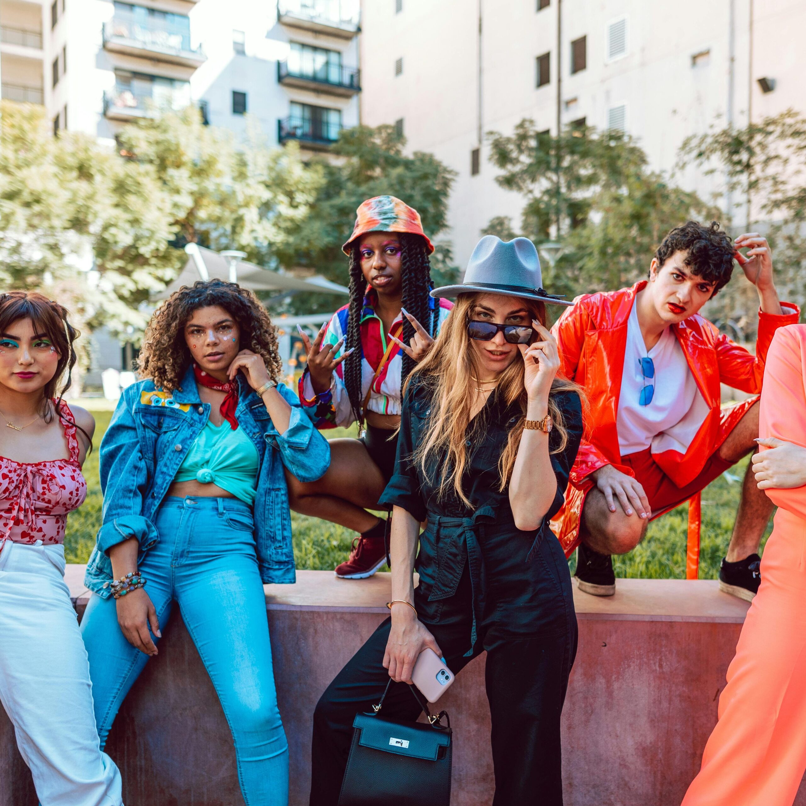 A diverse group of stylish young adults posing together in an urban outdoor setting.