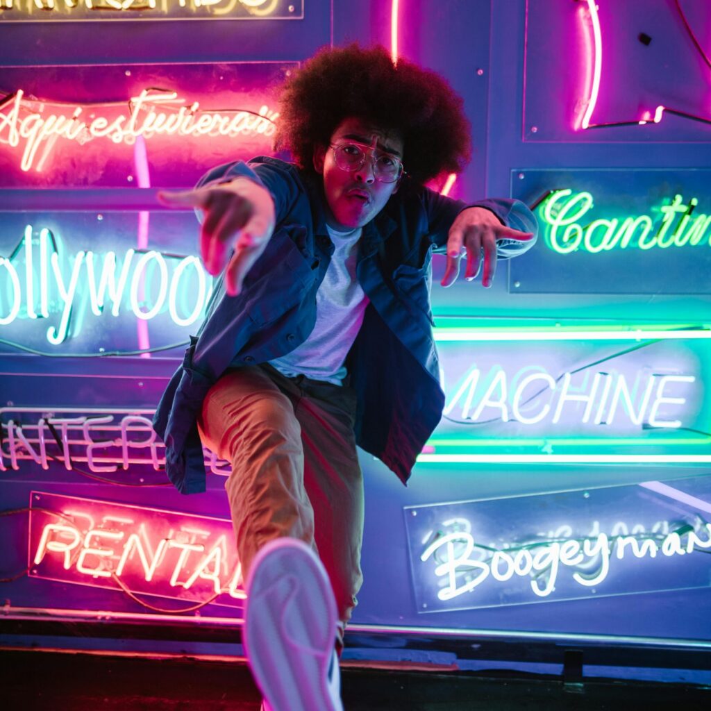 Energetic portrait of a man posing amid colorful neon signs, capturing a vibrant urban vibe.
